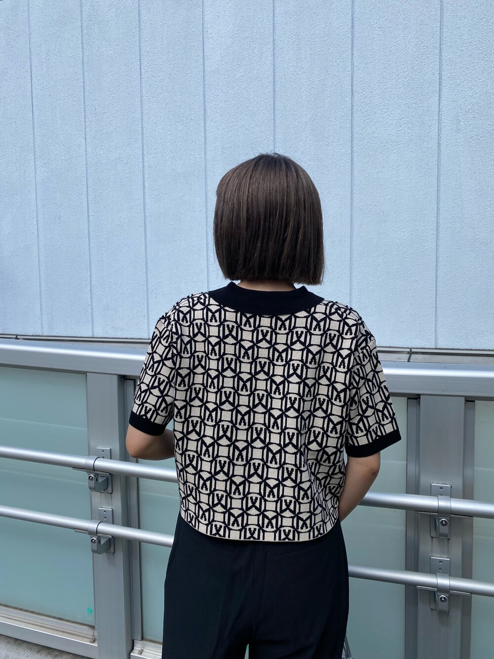 ブラック系のポロシャツ、グレー系のスラックス、ブラック系のサンダルを着用したレディースの春コーディネートの6枚目の写真