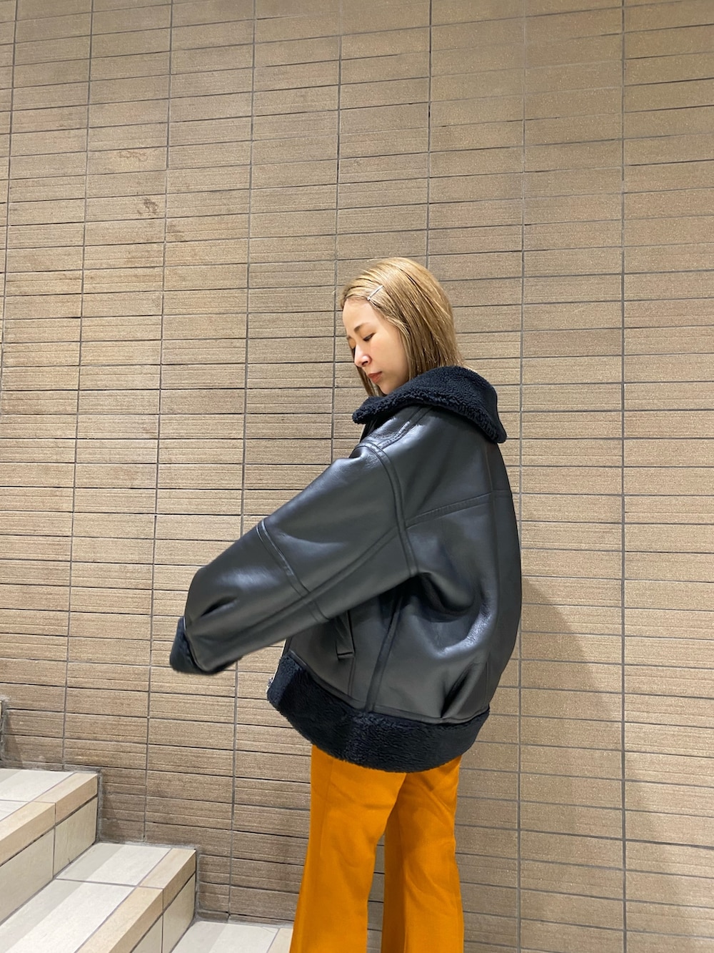 ブラック系のムートンコート、ホワイト系のTシャツ/カットソー、オレンジ系のその他パンツを着用したレディースの夏コーディネートの3枚目の写真