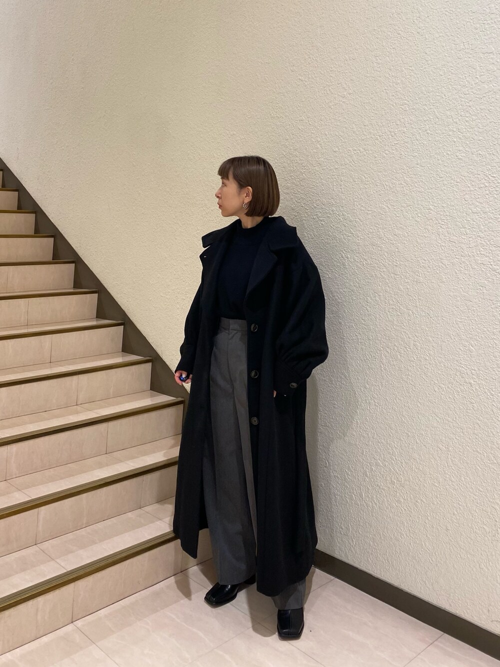 ブラック系のダウンジャケット/コート、パープル系のニット/セーター、グレー系のスラックスを着用したレディースの秋コーディネートの5枚目の写真