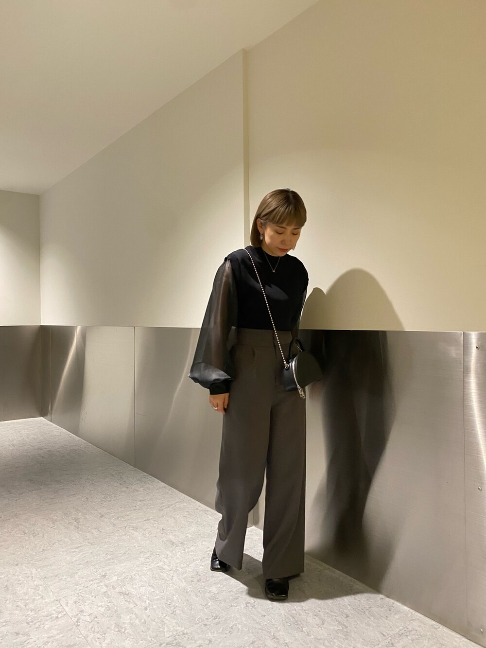 ブラック系のニット/セーター、グレー系のスラックスを着用したレディースの冬コーディネートの2枚目の写真