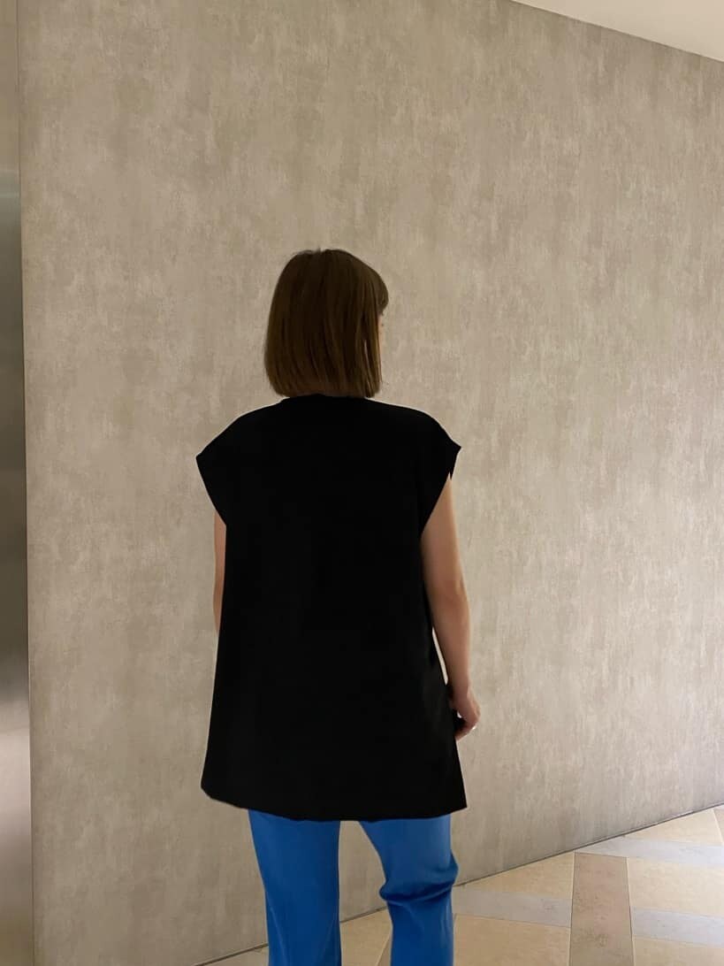 ブルー系のスラックス、ブラック系のベスト、ブラック系のタンクトップを着用したレディースの夏コーディネートの5枚目の写真