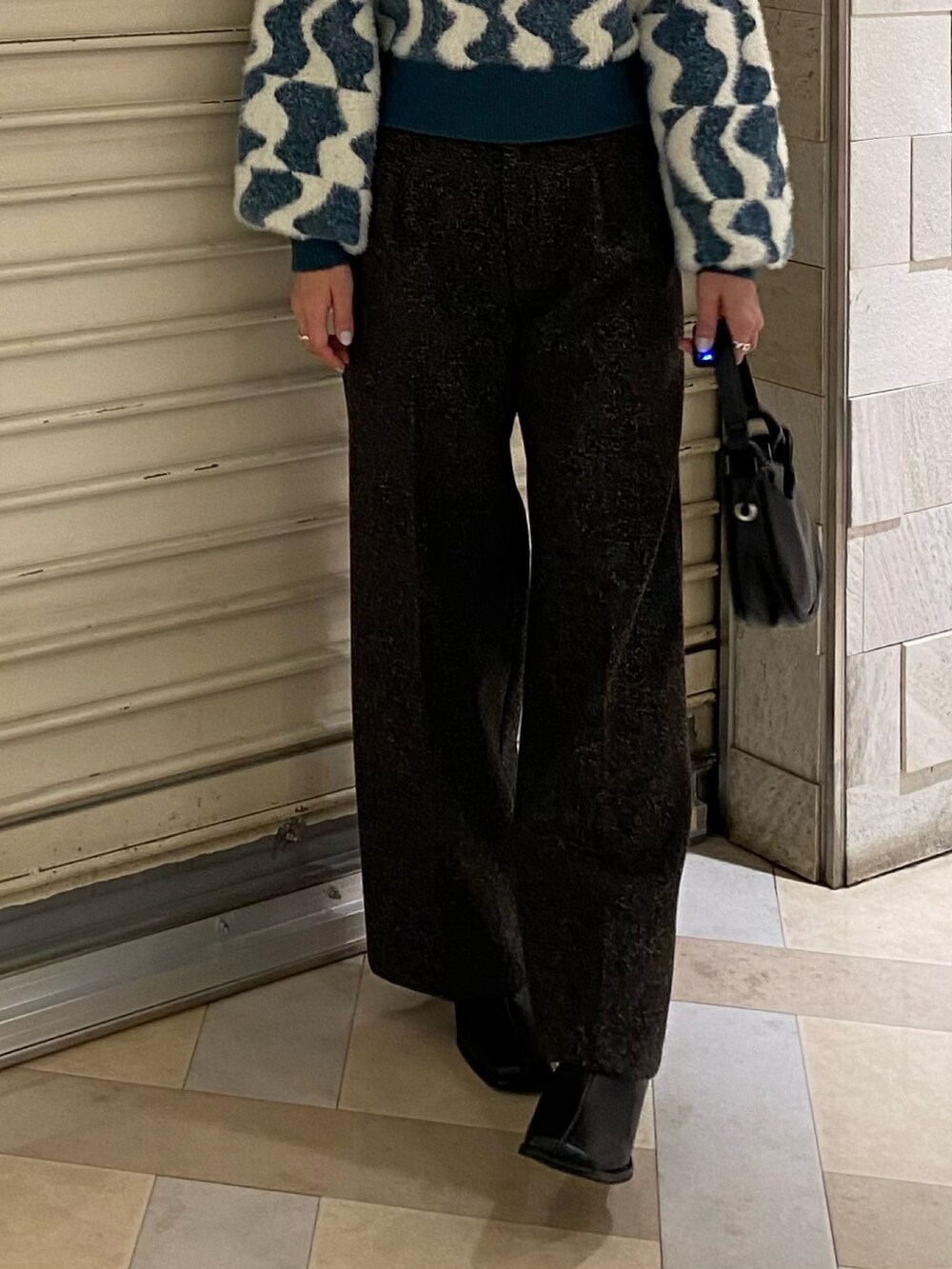 グリーン系のニット/セーター、ブラック系のスラックス、ブラック系のブーツを着用したレディースの秋コーディネートの7枚目の写真