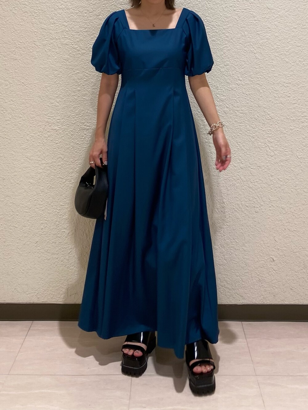 ブルー系のワンピース、ブラック系のサンダル、ブラック系のハンドバッグを着用したレディースの夏コーディネートの3枚目の写真