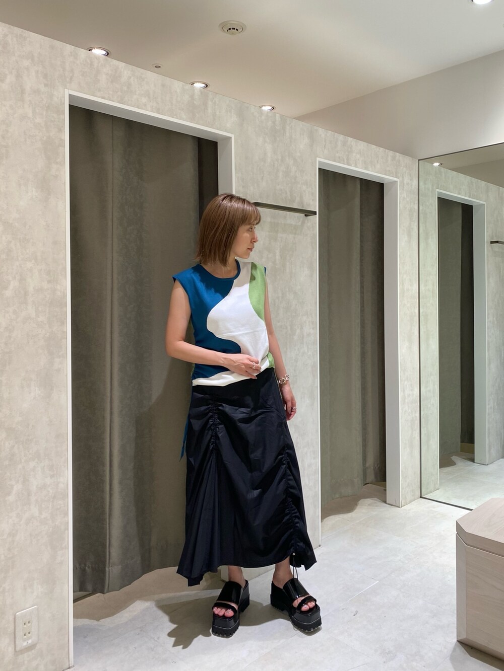 ブルー系のニット/セーター、ブラック系のスカート、ブラック系のサンダルを着用したレディースの夏コーディネートの2枚目の写真