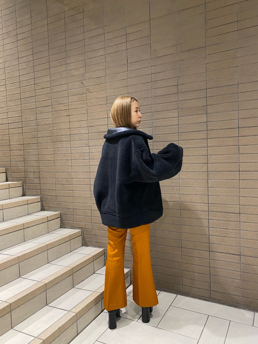 ブラック系のムートンコート、ホワイト系のTシャツ/カットソー、オレンジ系のその他パンツを着用したレディースの夏コーディネートの4枚目の写真