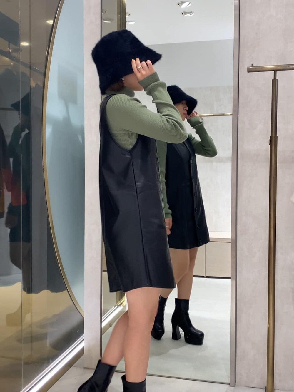 ブラック系のブーツ、ブラック系のワンピース、グリーン系のニット/セーターを着用したレディースの秋コーディネートの3枚目の写真