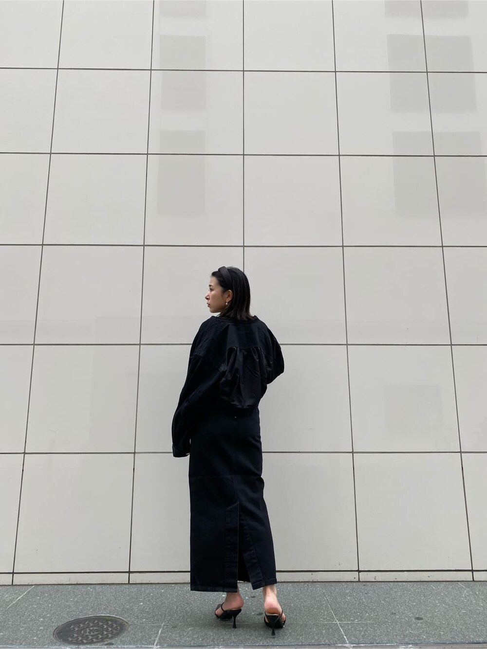 ブラック系のスカート、ブラック系のパンプス、ブラック系のブルゾンを着用したレディースの夏コーディネートの2枚目の写真