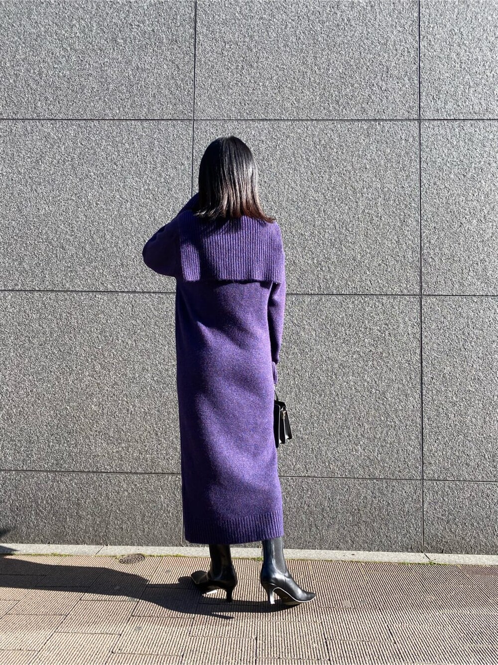 ブラック系のハンドバッグ、パープル系のワンピース、ブラック系のブーツを着用したレディースの冬コーディネートの2枚目の写真