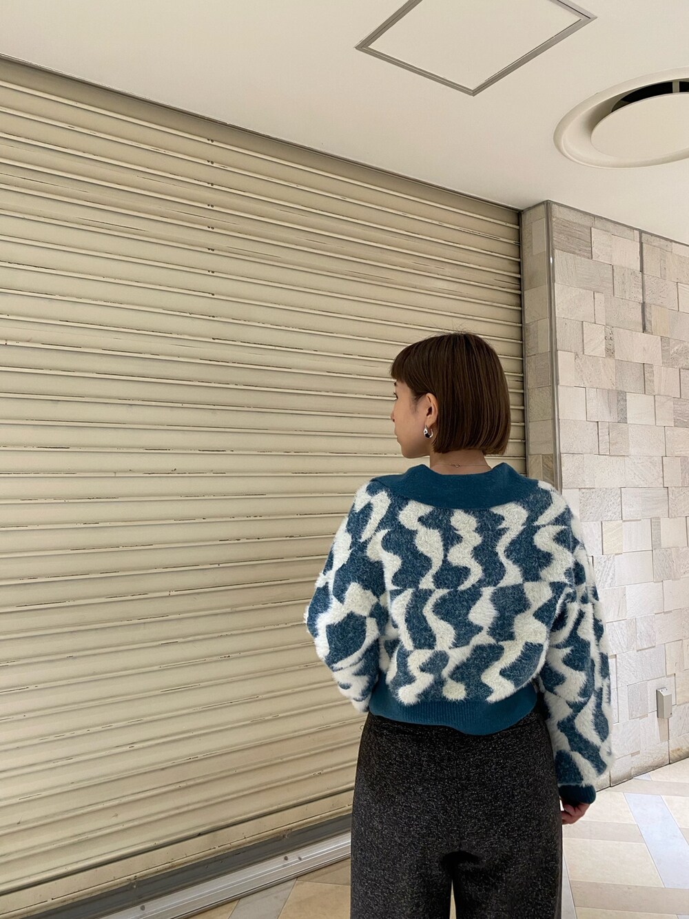 グリーン系のニット/セーター、ブラック系のスラックス、ブラック系のブーツを着用したレディースの秋コーディネートの6枚目の写真