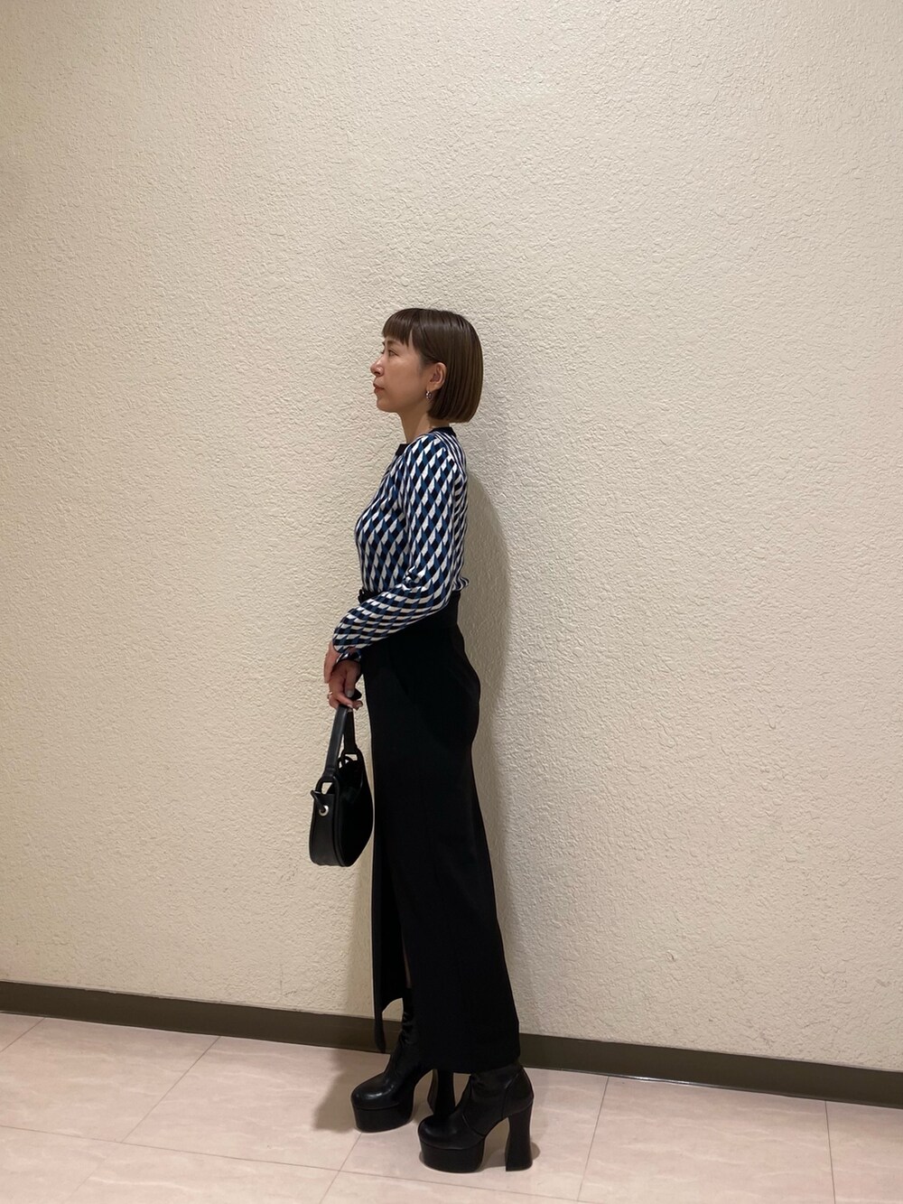 ブラック系のニット/セーター、ブラック系のスカート、ブラック系のブーツを着用したレディースの秋コーディネートの2枚目の写真