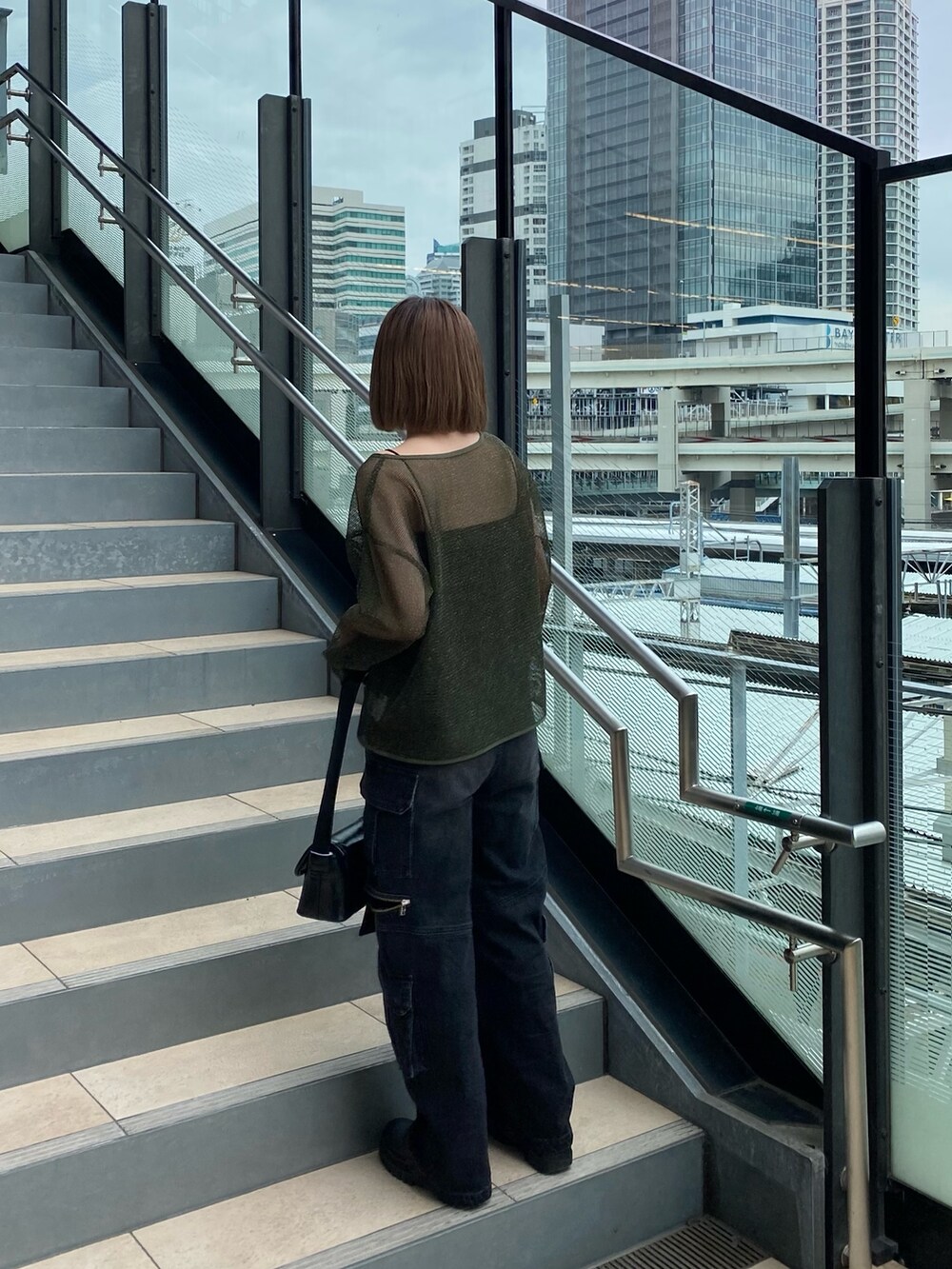 グリーン系のTシャツ/カットソー、ブラック系のデニムパンツ、ブラック系のショルダーバッグを着用したレディースの冬コーディネートの2枚目の写真