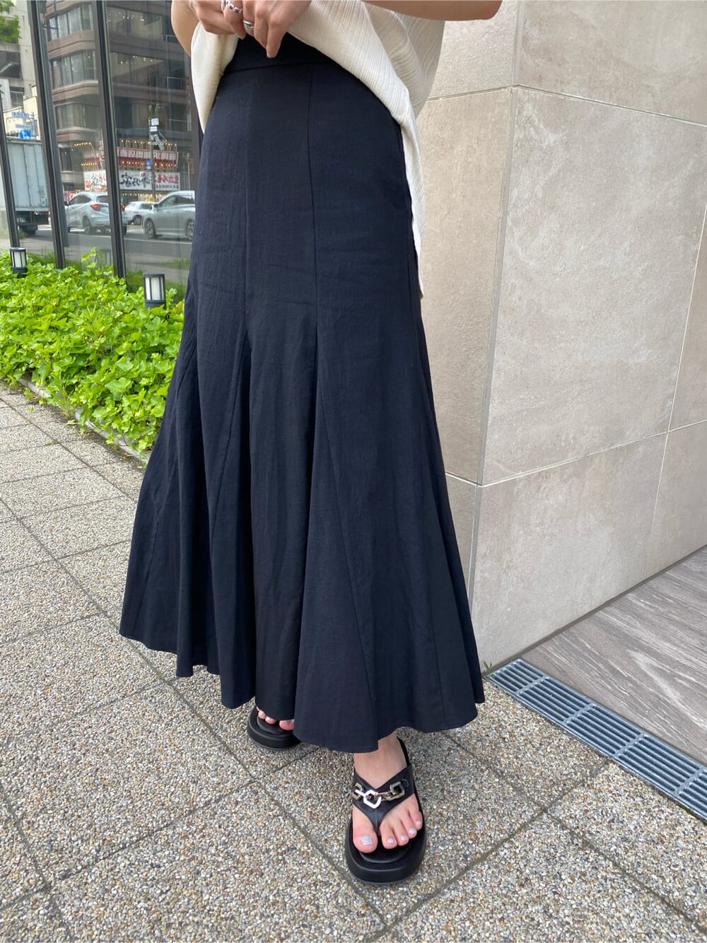 ブラック系のスカート、ブラック系のサンダル、ホワイト系のTシャツ/カットソーを着用したレディースの夏コーディネートの4枚目の写真