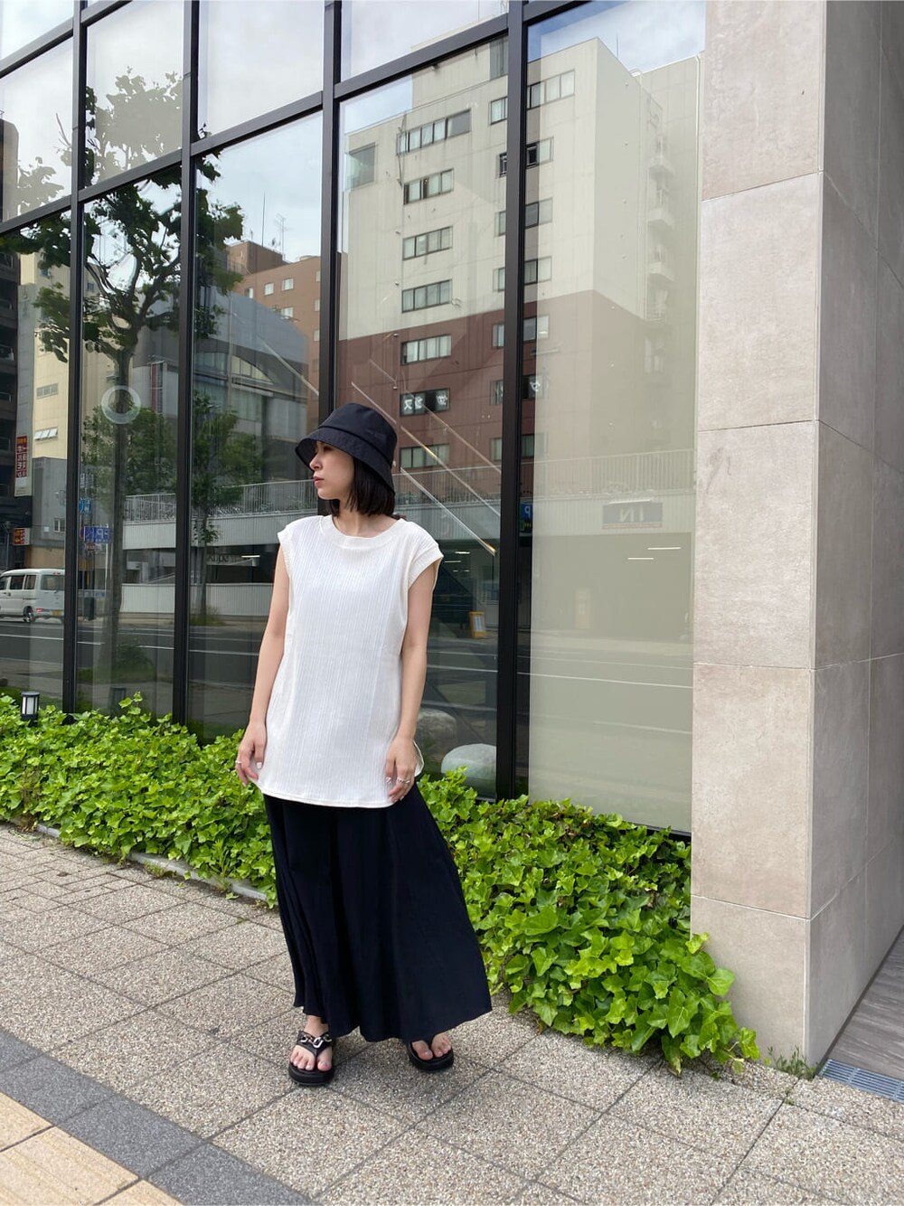 ブラック系のスカート、ブラック系のサンダル、ホワイト系のTシャツ/カットソーを着用したレディースの夏コーディネートの2枚目の写真