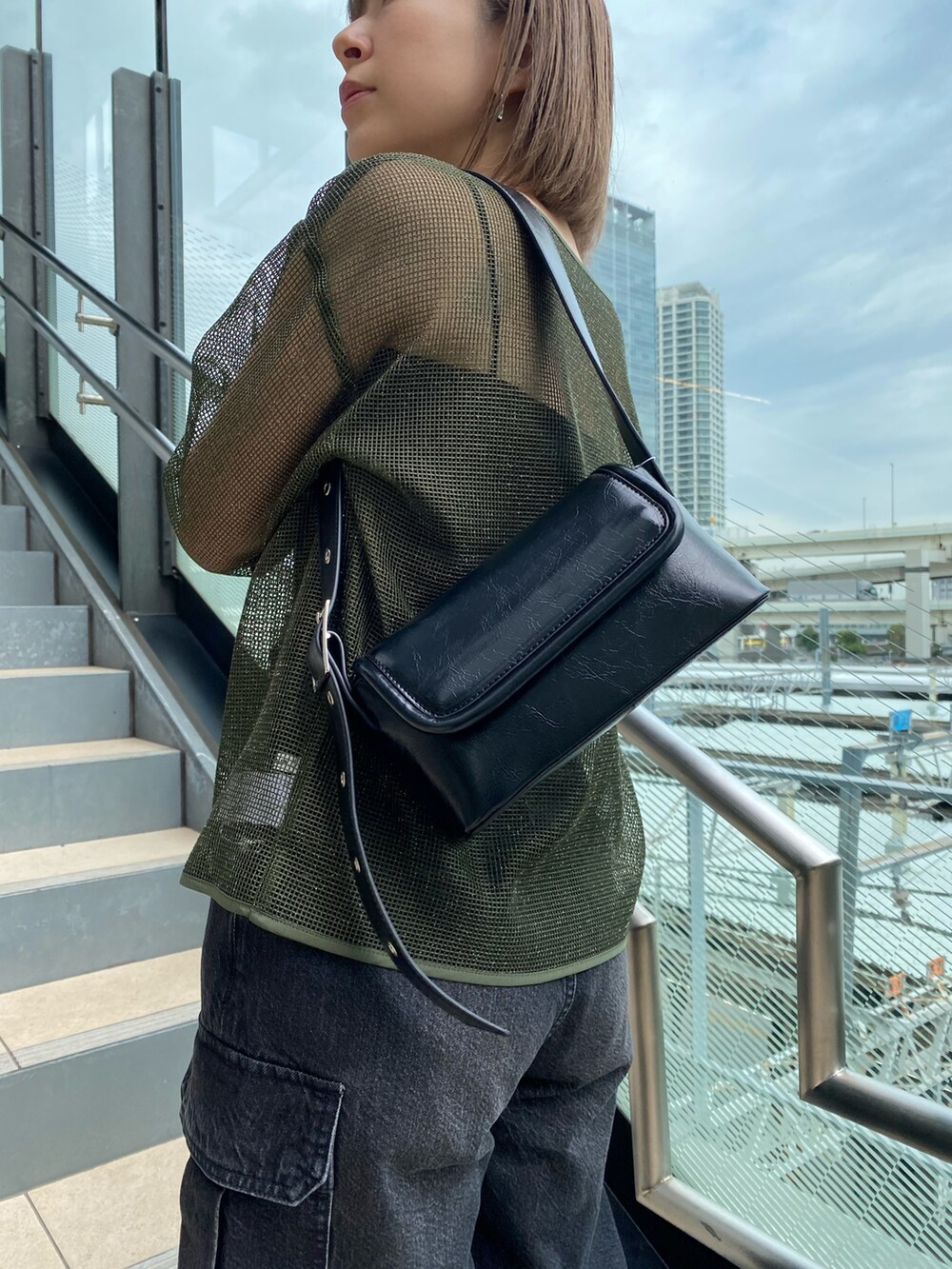 グリーン系のTシャツ/カットソー、ブラック系のデニムパンツ、ブラック系のショルダーバッグを着用したレディースの冬コーディネートの6枚目の写真