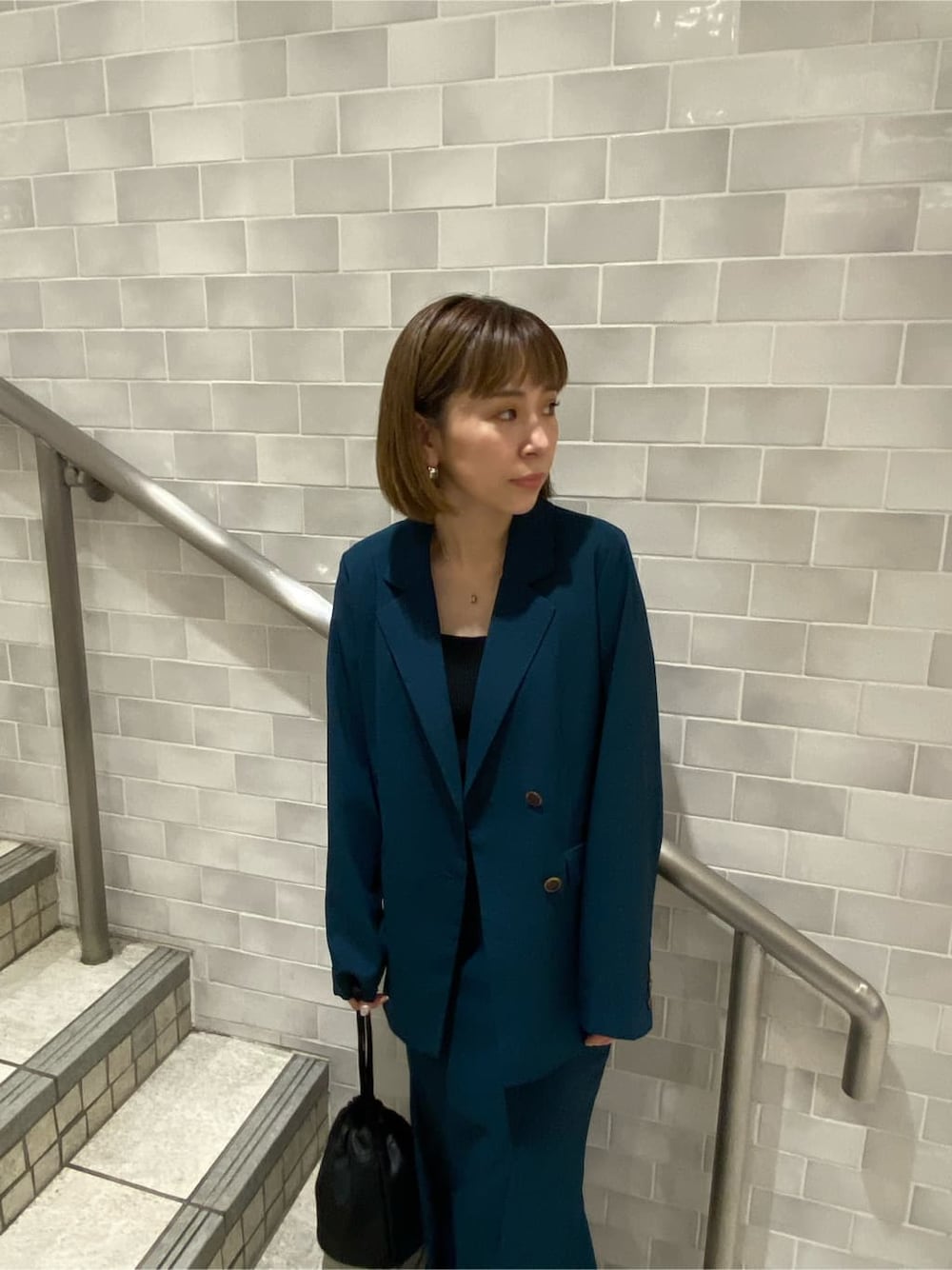 ブラック系のタンクトップ、グリーン系のテーラードジャケット、グリーン系のスカートを着用したレディースの夏コーディネートの4枚目の写真