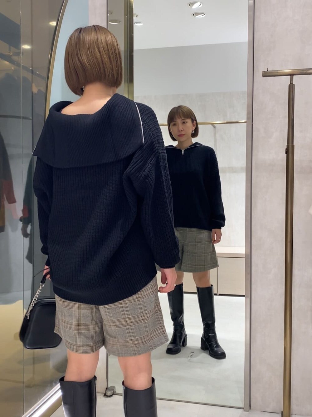 ブラック系のブーツ、ブラック系のニット/セーター、ブラック系のショルダーバッグを着用したレディースの秋コーディネートの3枚目の写真