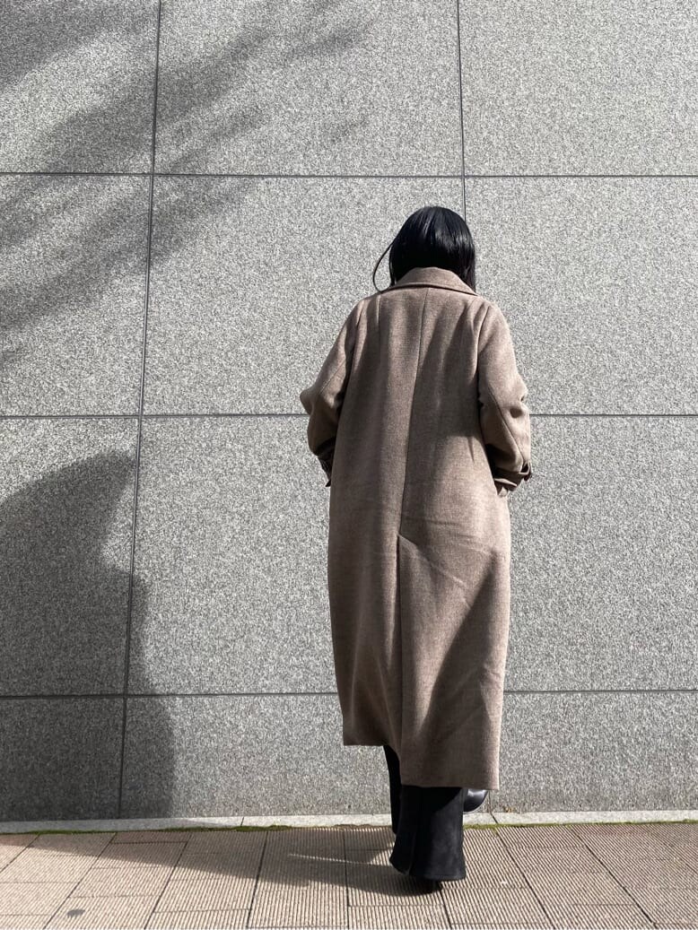 ブラック系のスラックス、ベージュ系のチェスターコート、ブラック系のブーツを着用したレディースの秋コーディネートの2枚目の写真