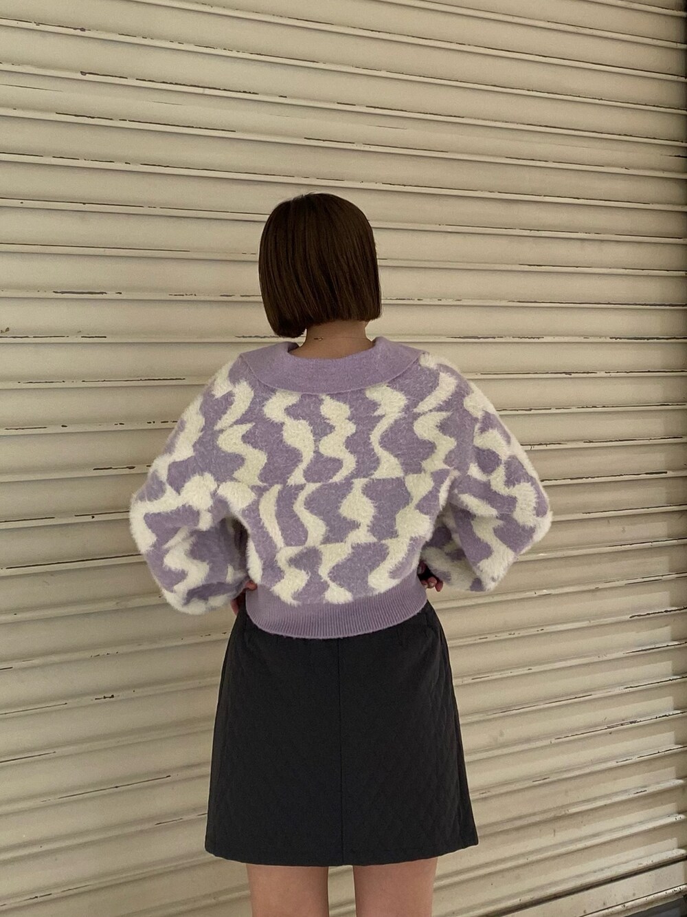 パープル系のニット/セーター、グレー系のスカート、ブラック系のブーツを着用したレディースの秋コーディネートの6枚目の写真