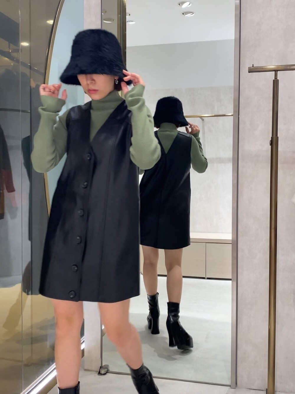 ブラック系のブーツ、ブラック系のワンピース、グリーン系のニット/セーターを着用したレディースの秋コーディネートの2枚目の写真