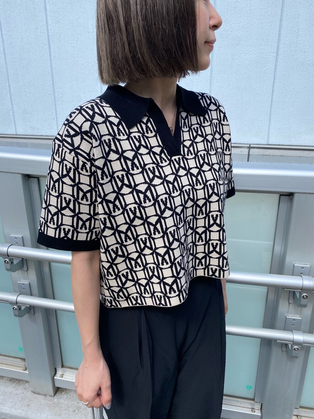 ブラック系のポロシャツ、グレー系のスラックス、ブラック系のサンダルを着用したレディースの春コーディネートの5枚目の写真