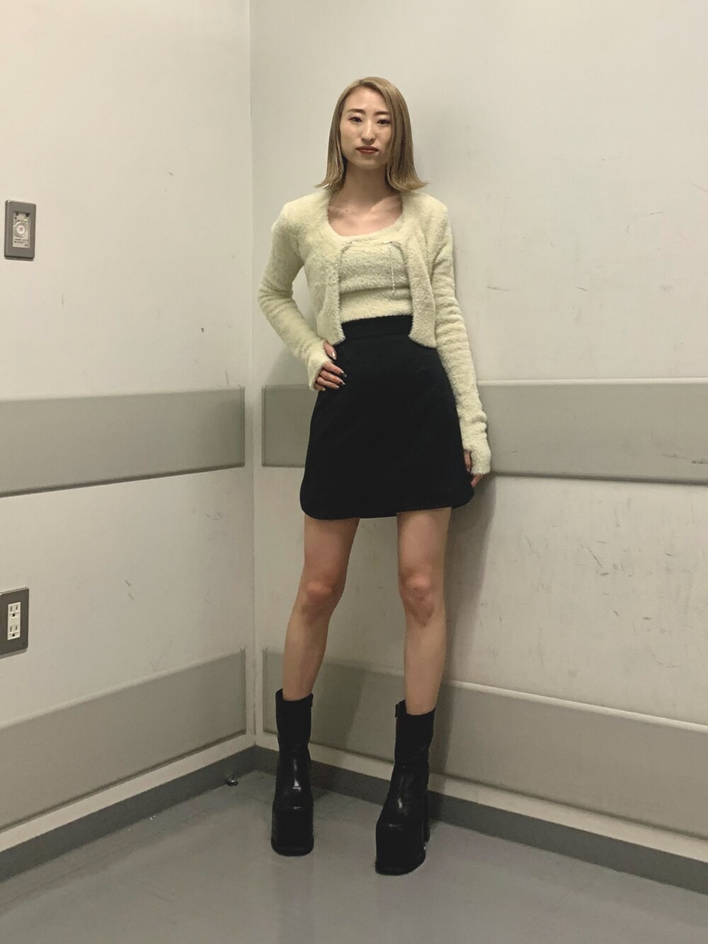ブラック系のスカート、ホワイト系のニット/セーター、ブラック系のブーツを着用したレディースの冬コーディネートの2枚目の写真