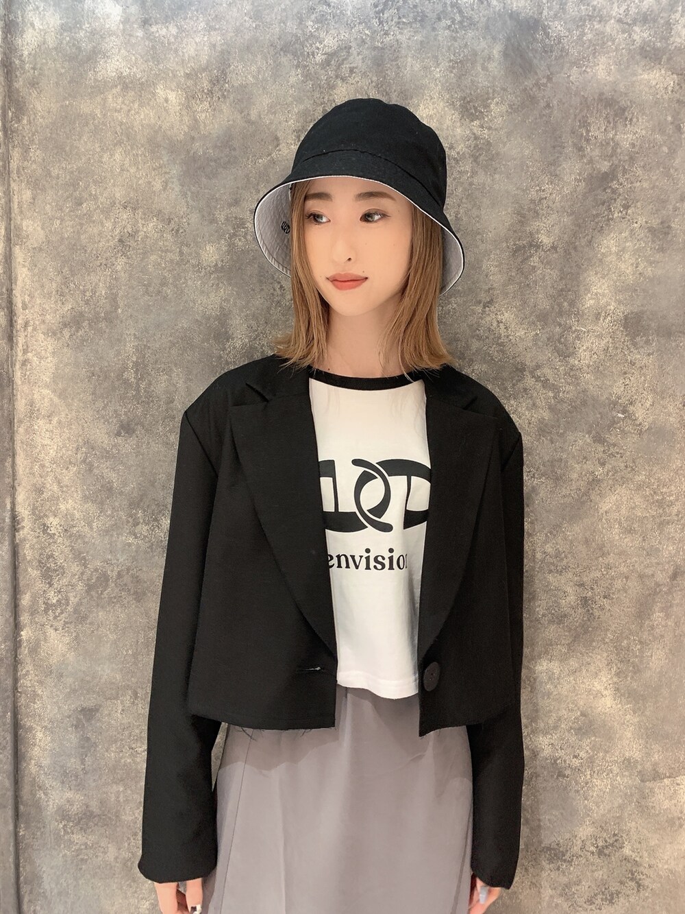 ブラック系のテーラードジャケット、ホワイト系のTシャツ/カットソー、グレー系のスカートを着用したレディースの冬コーディネートの5枚目の写真