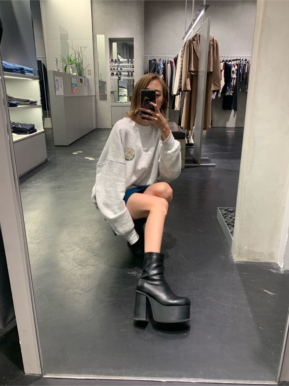 グレー系のスウェット、ブルー系のスカート、ブラック系のブーツを着用したレディースの秋コーディネートの4枚目の写真