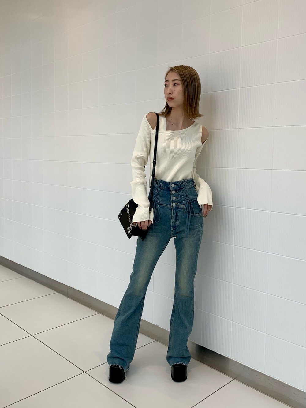 ブラック系のショルダーバッグ、ホワイト系のニット/セーター、ブラック系のブーツを着用したレディースの冬コーディネートの4枚目の写真