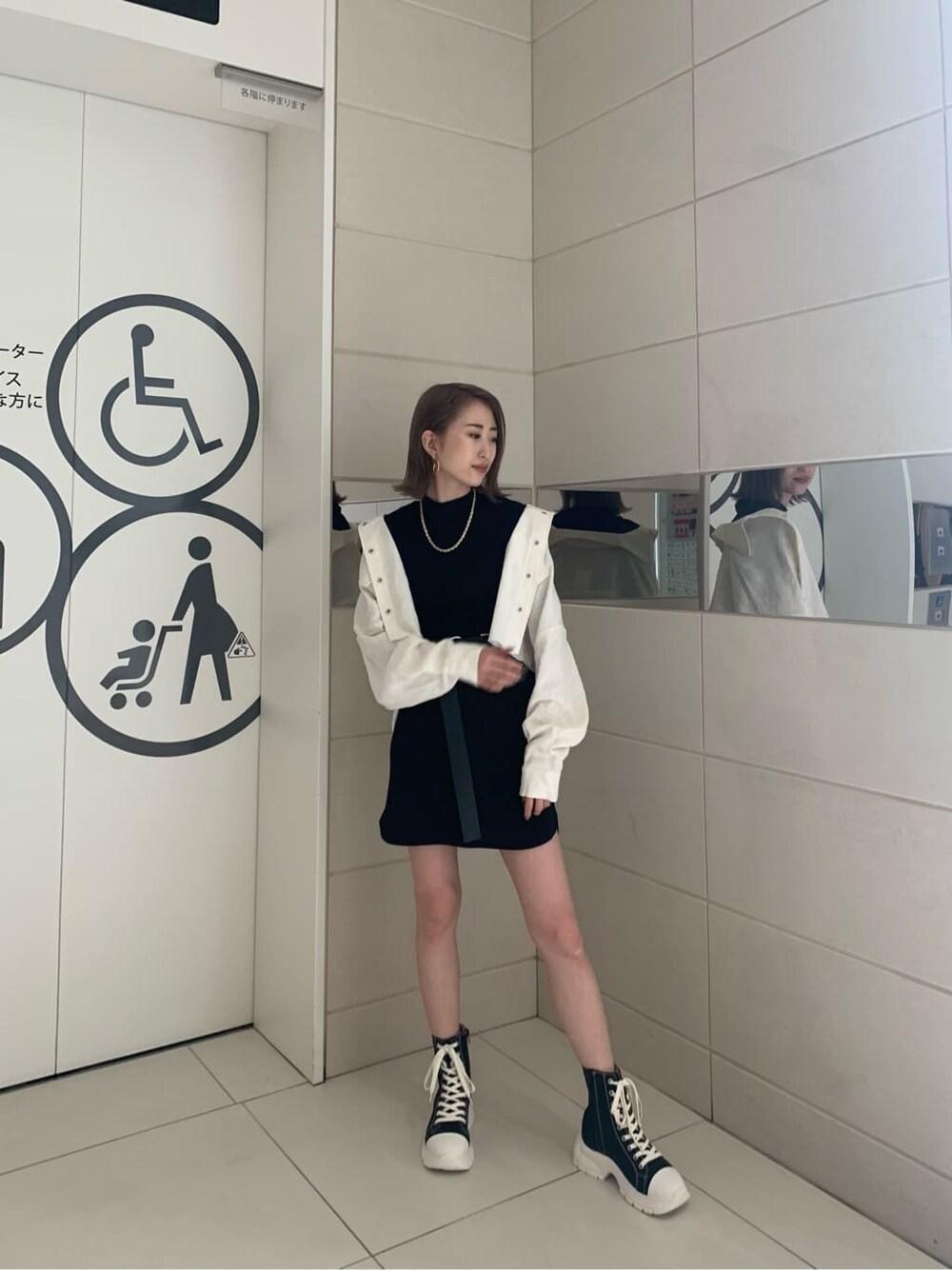 ホワイト系のブルゾン、ブラック系のスニーカー、ブラック系のワンピースを着用したレディースの春コーディネートの2枚目の写真