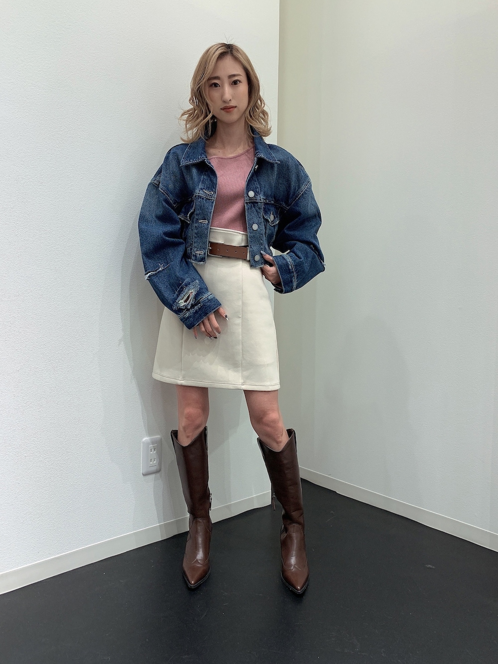 ブルー系のデニムジャケット、ピンク系のニット/セーター、ホワイト系のスカートを着用したレディースの春コーディネートの4枚目の写真
