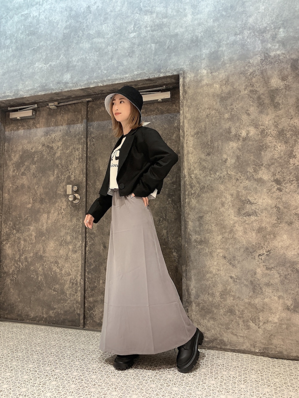 ブラック系のテーラードジャケット、ホワイト系のTシャツ/カットソー、グレー系のスカートを着用したレディースの冬コーディネートの4枚目の写真