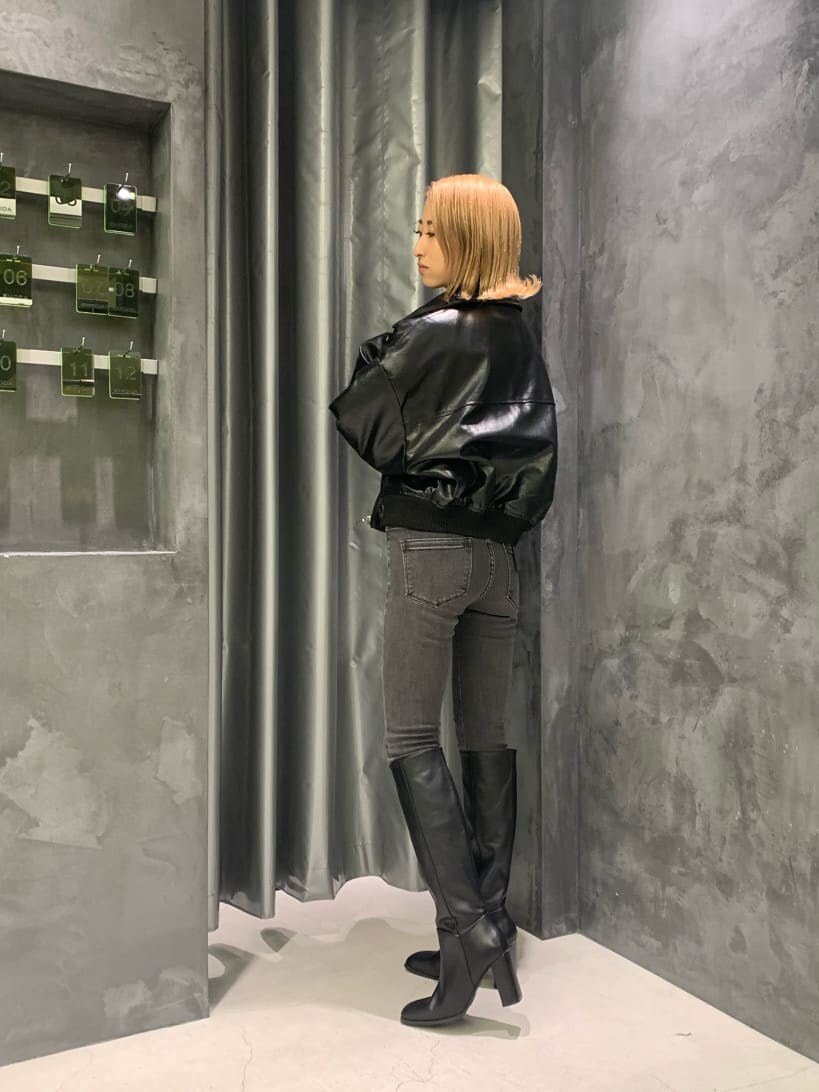 ブラック系のブーツ、グレー系のデニムパンツ、ブラック系のブルゾンを着用したレディースの秋コーディネートの2枚目の写真