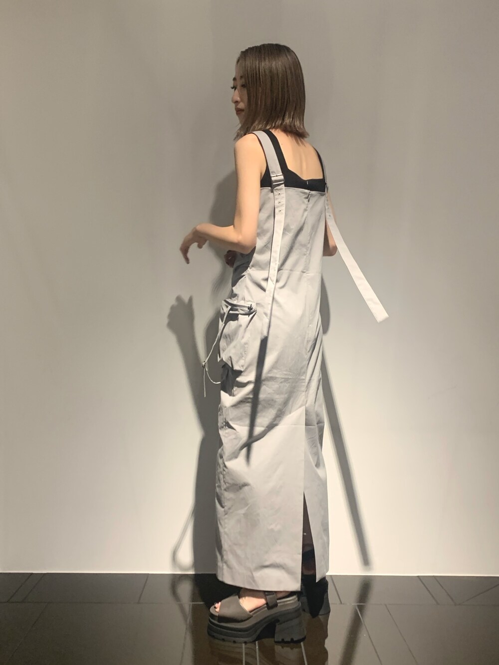 グレー系のワンピース、グレー系のサンダル、ブラック系のタンクトップを着用したレディースの夏コーディネートの4枚目の写真