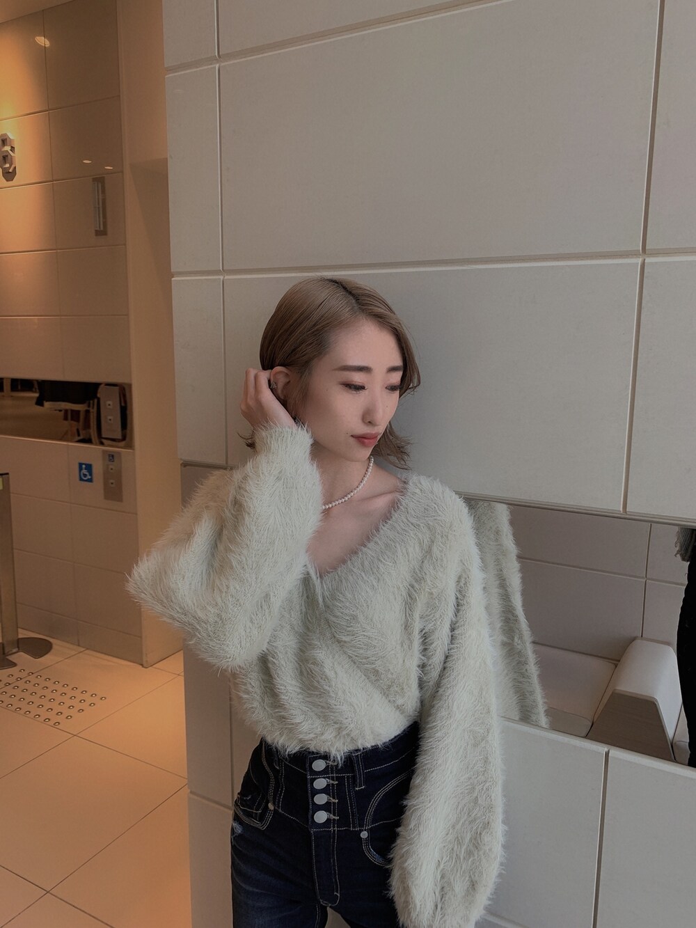 グレー系のニット/セーター、ブルー系のデニムパンツ、ブラック系のブーツを着用したレディースの冬コーディネートの6枚目の写真