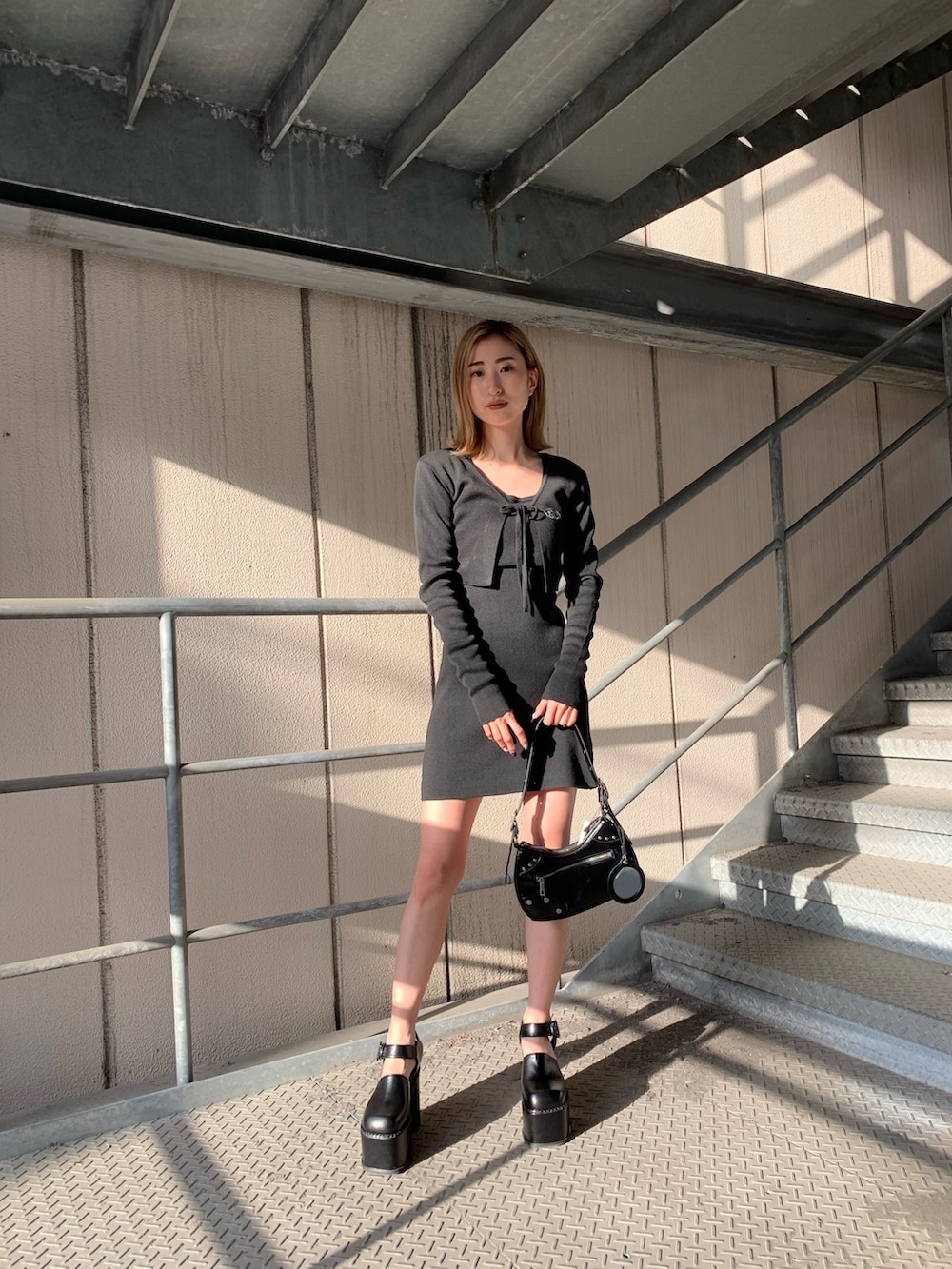ブラック系のワンピース、ブラック系のサンダル、ブラック系のハンドバッグを着用したレディースの春コーディネートの2枚目の写真