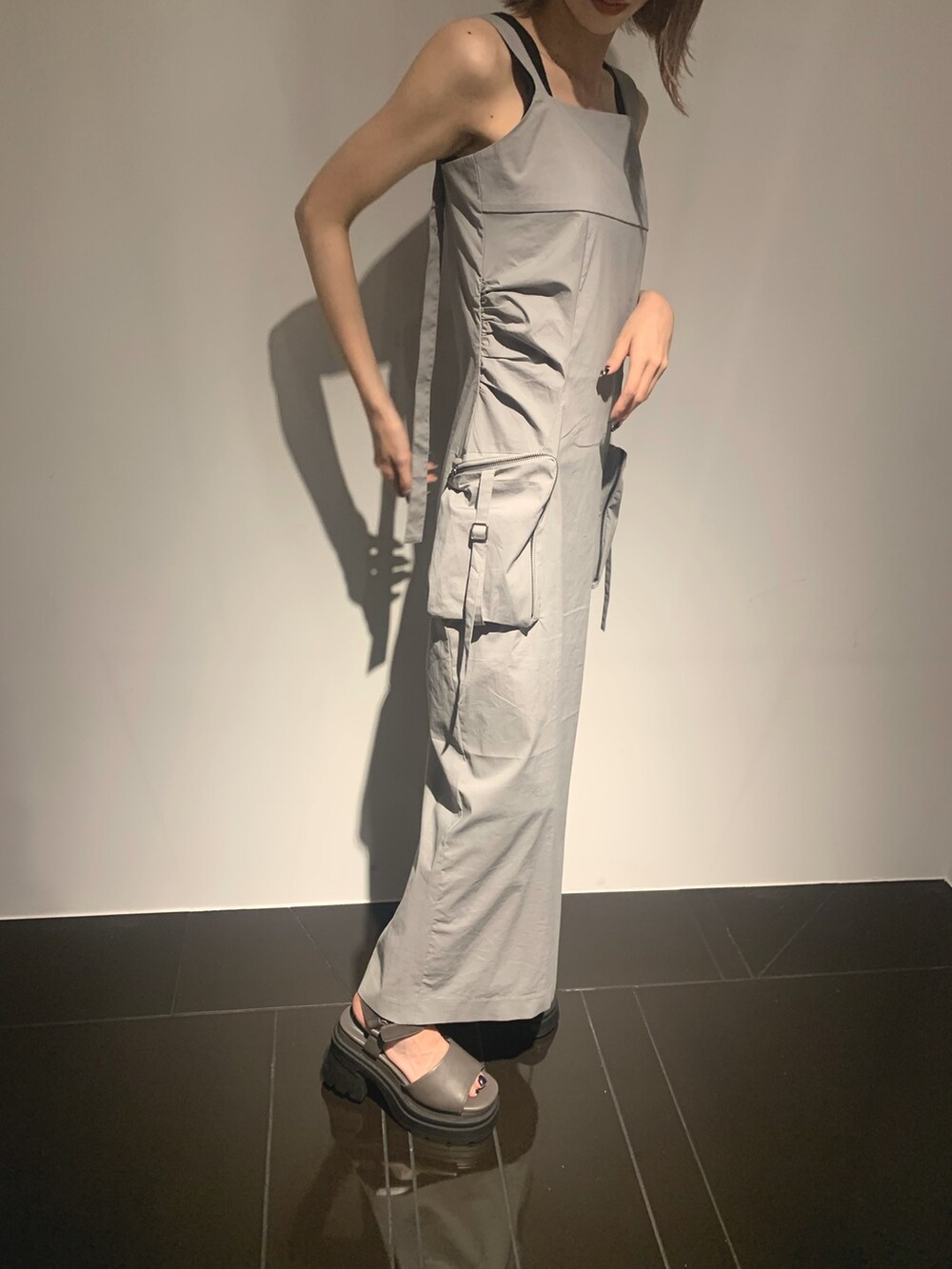 グレー系のワンピース、グレー系のサンダル、ブラック系のタンクトップを着用したレディースの夏コーディネートの6枚目の写真