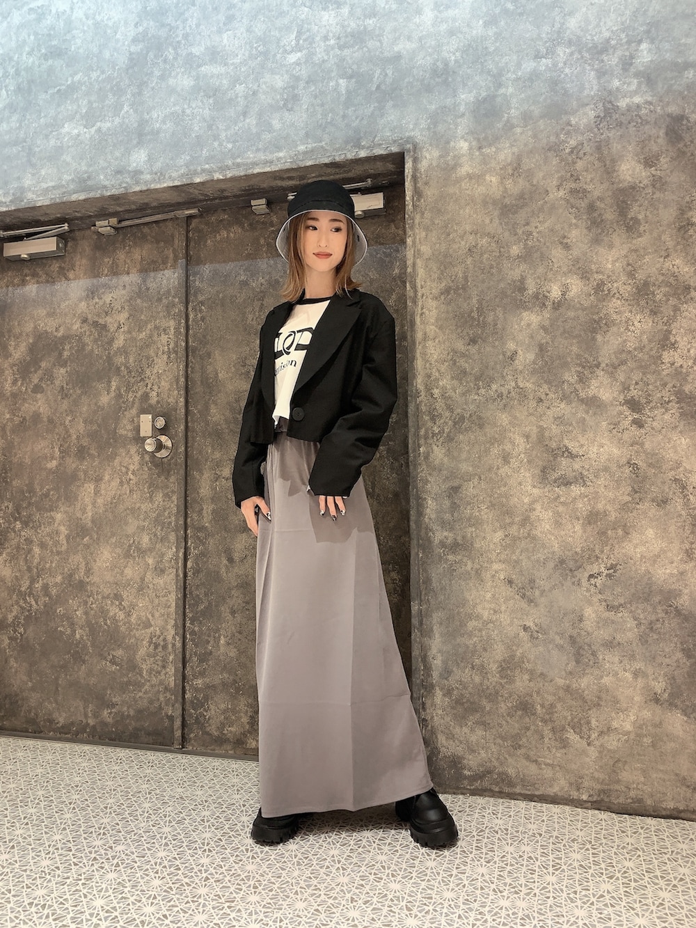 ブラック系のテーラードジャケット、ホワイト系のTシャツ/カットソー、グレー系のスカートを着用したレディースの冬コーディネートの3枚目の写真