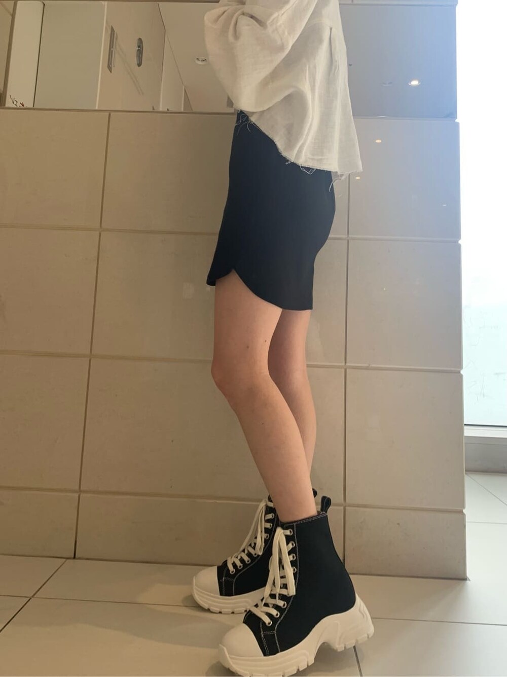 ホワイト系のブルゾン、ブラック系のスニーカー、ブラック系のワンピースを着用したレディースの春コーディネートの4枚目の写真