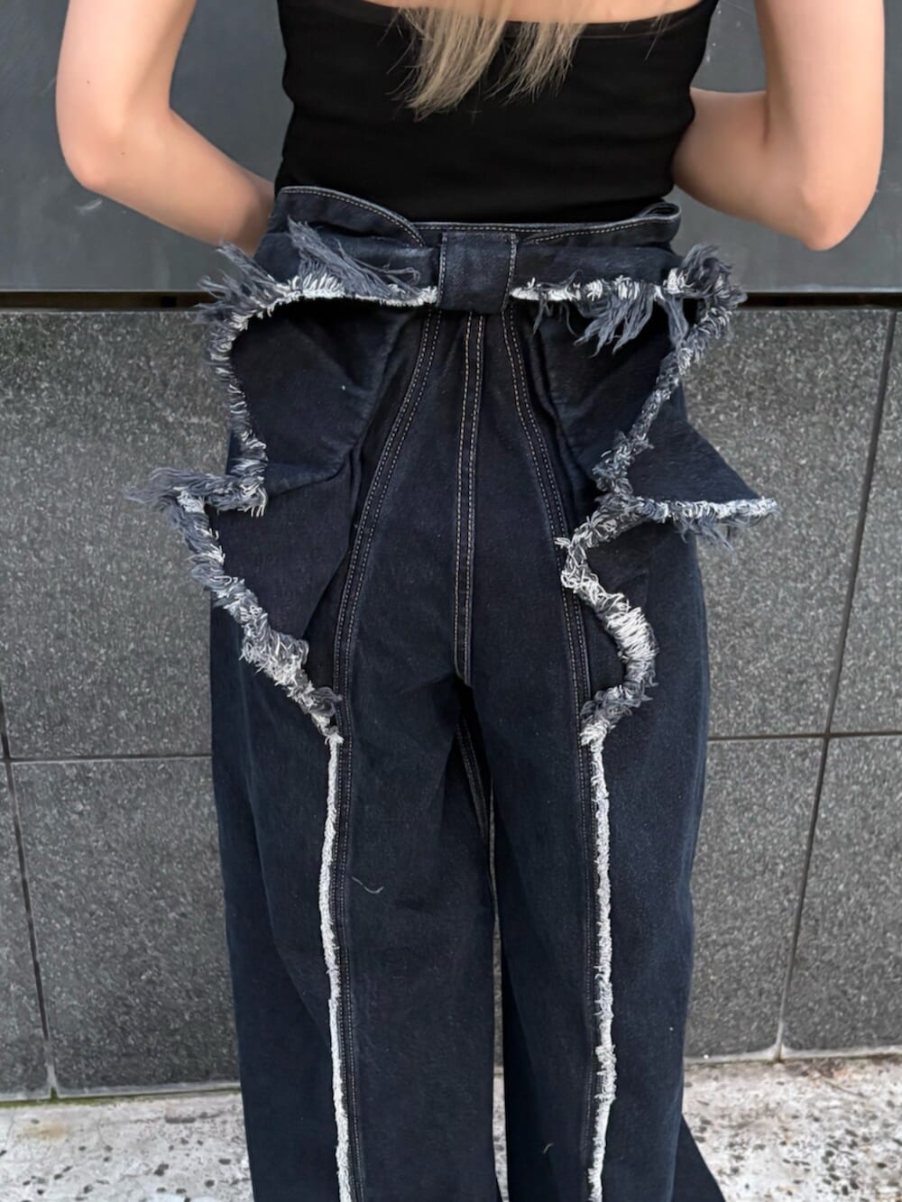 ブラック系のタンクトップ、ブルー系のデニムパンツ、ブラック系のサンダルを着用したレディースの春コーディネートの9枚目の写真
