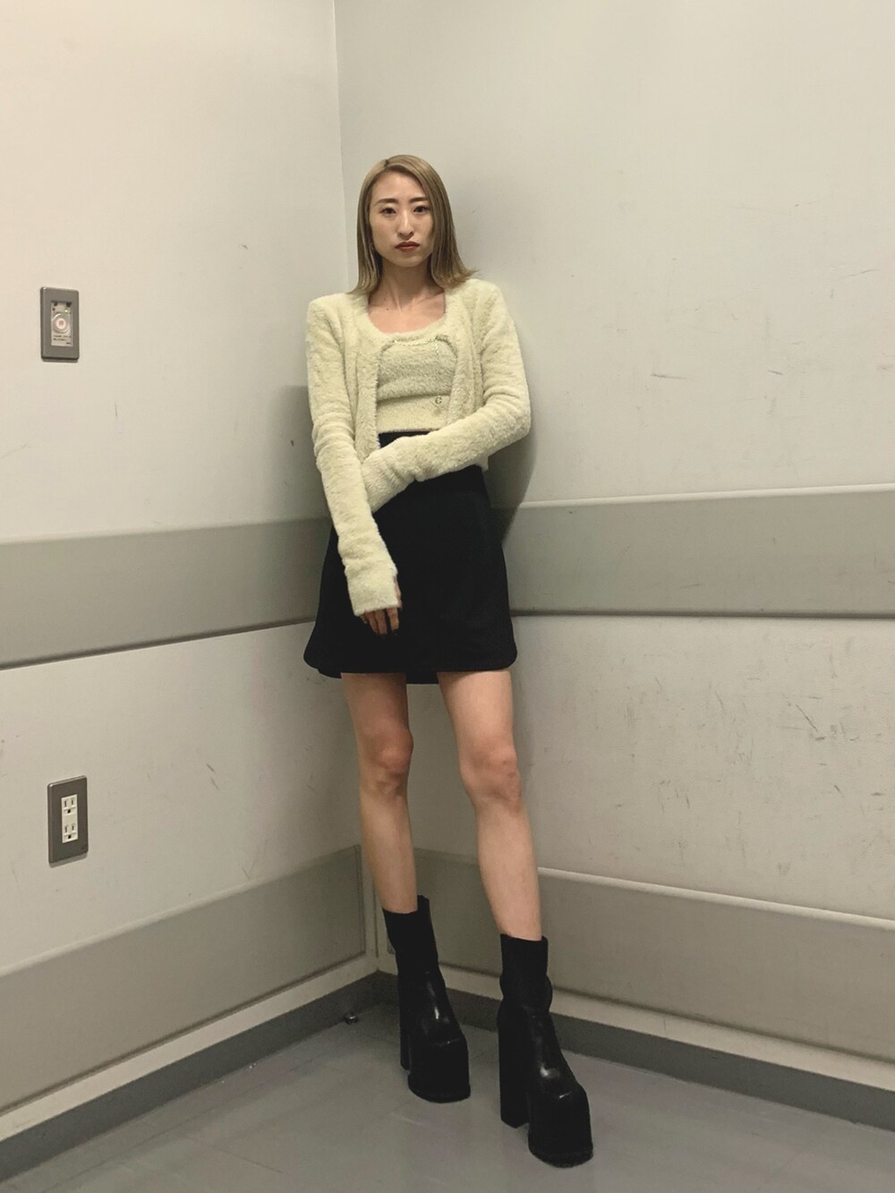 ブラック系のスカート、ホワイト系のニット/セーター、ブラック系のブーツを着用したレディースの冬コーディネートの3枚目の写真