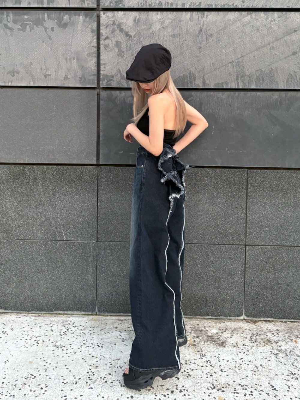 ブラック系のタンクトップ、ブルー系のデニムパンツ、ブラック系のサンダルを着用したレディースの春コーディネートの4枚目の写真