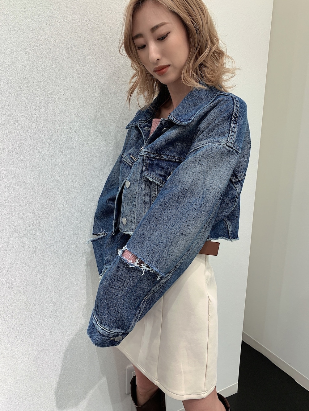 ブルー系のデニムジャケット、ピンク系のニット/セーター、ホワイト系のスカートを着用したレディースの春コーディネートの5枚目の写真