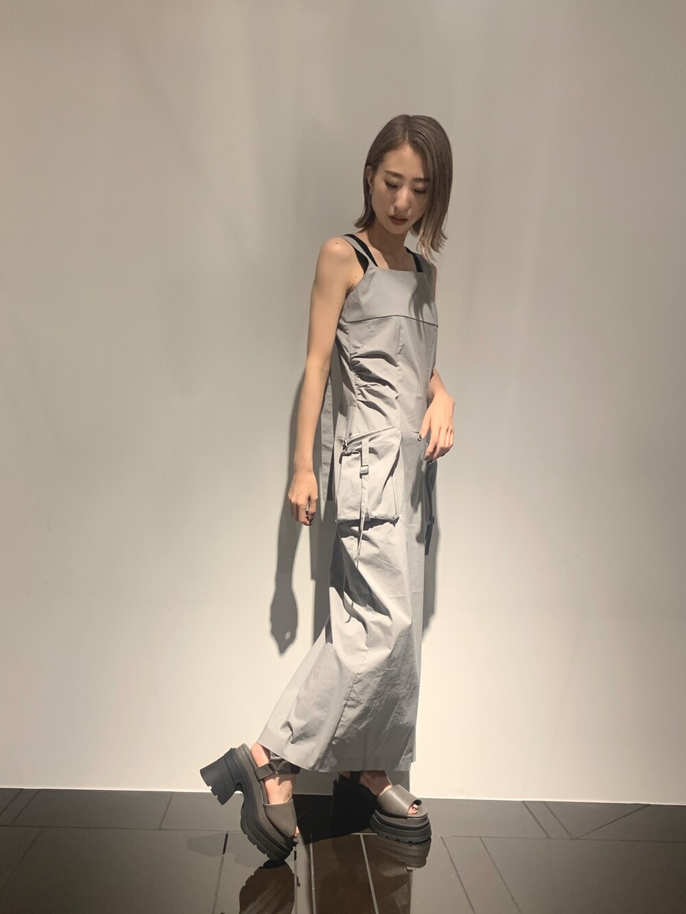 グレー系のワンピース、グレー系のサンダル、ブラック系のタンクトップを着用したレディースの夏コーディネートの2枚目の写真