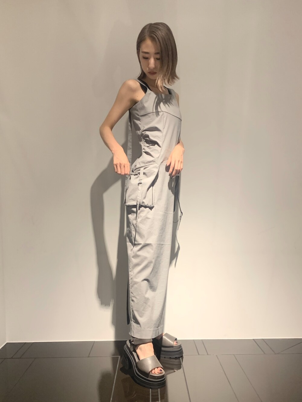 グレー系のワンピース、グレー系のサンダル、ブラック系のタンクトップを着用したレディースの夏コーディネートの5枚目の写真