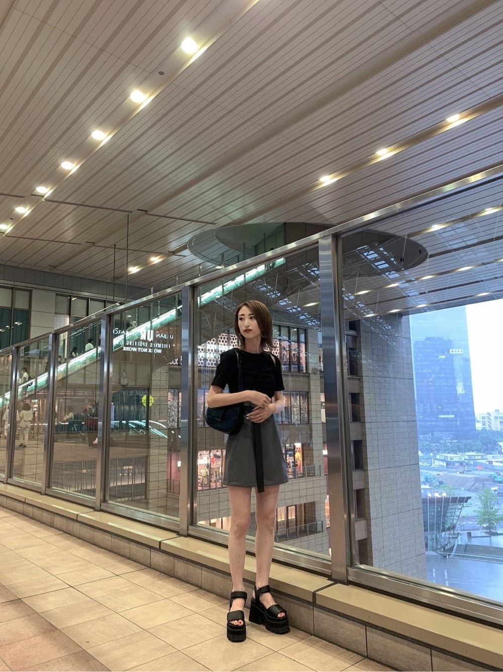 グレー系のスカート、ブラック系のサンダル、ブラック系のハンドバッグを着用したレディースの夏コーディネートの2枚目の写真