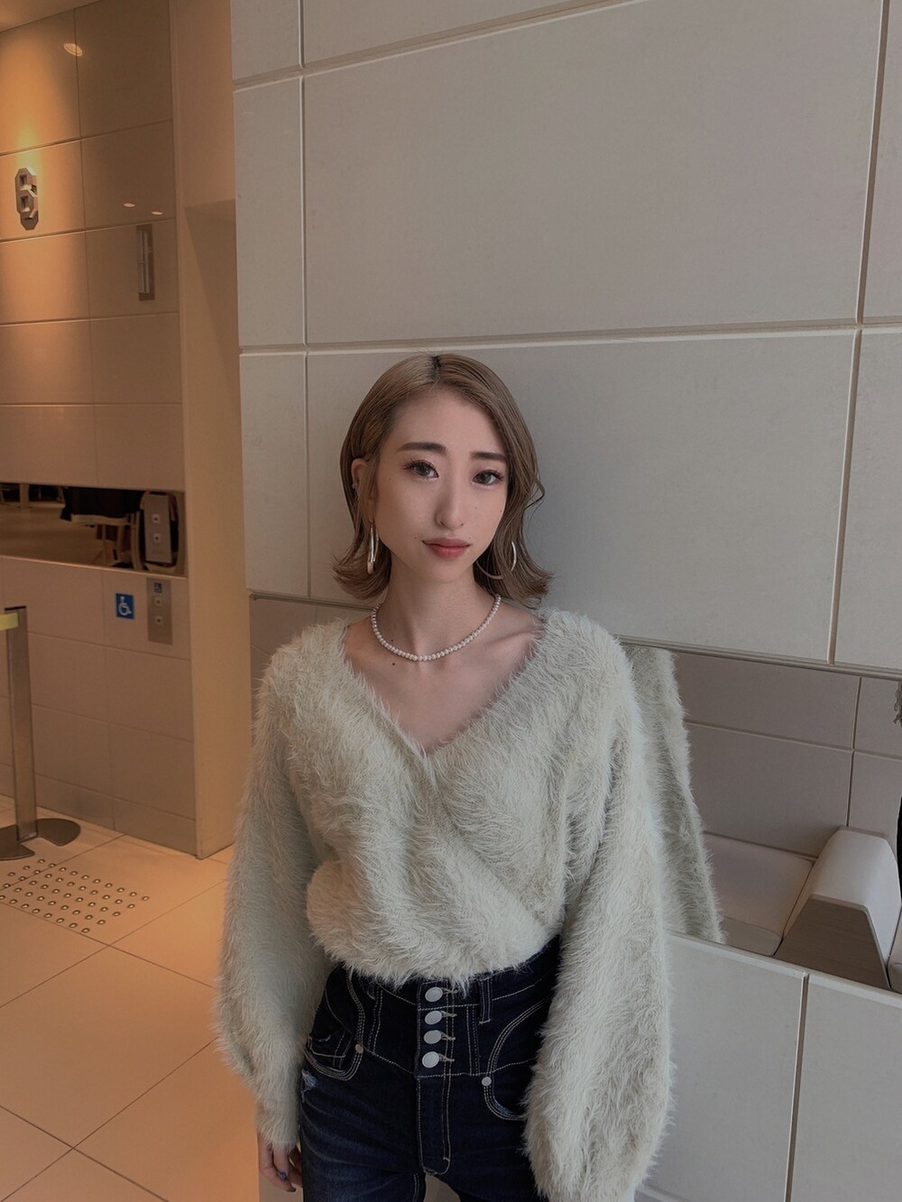 グレー系のニット/セーター、ブルー系のデニムパンツ、ブラック系のブーツを着用したレディースの冬コーディネートの7枚目の写真