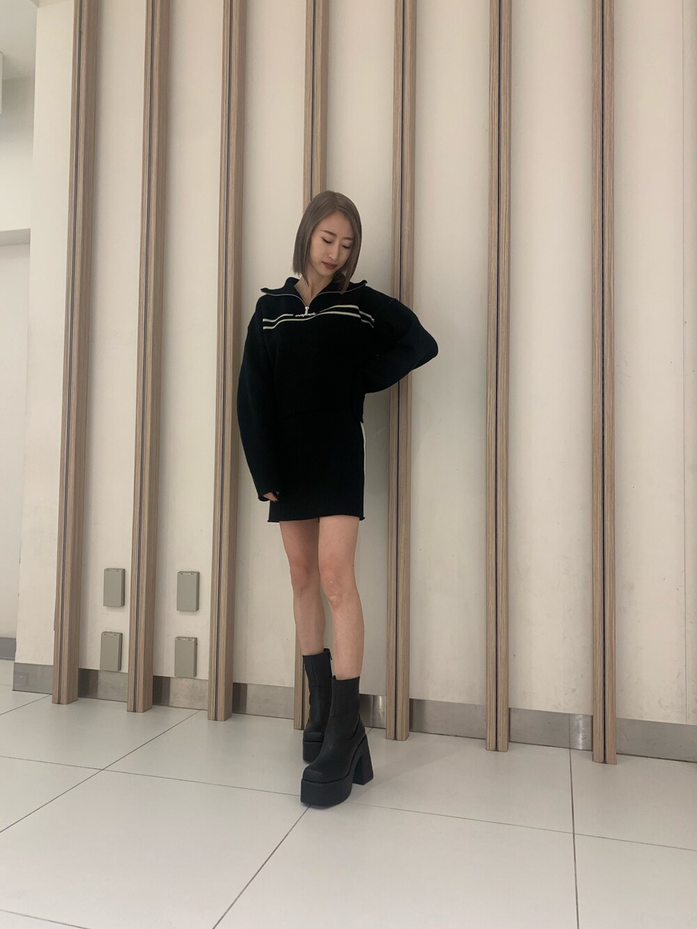 ブラック系のニット/セーター、ブラック系のスカート、ブラック系のブーツを着用したレディースの秋コーディネートの2枚目の写真