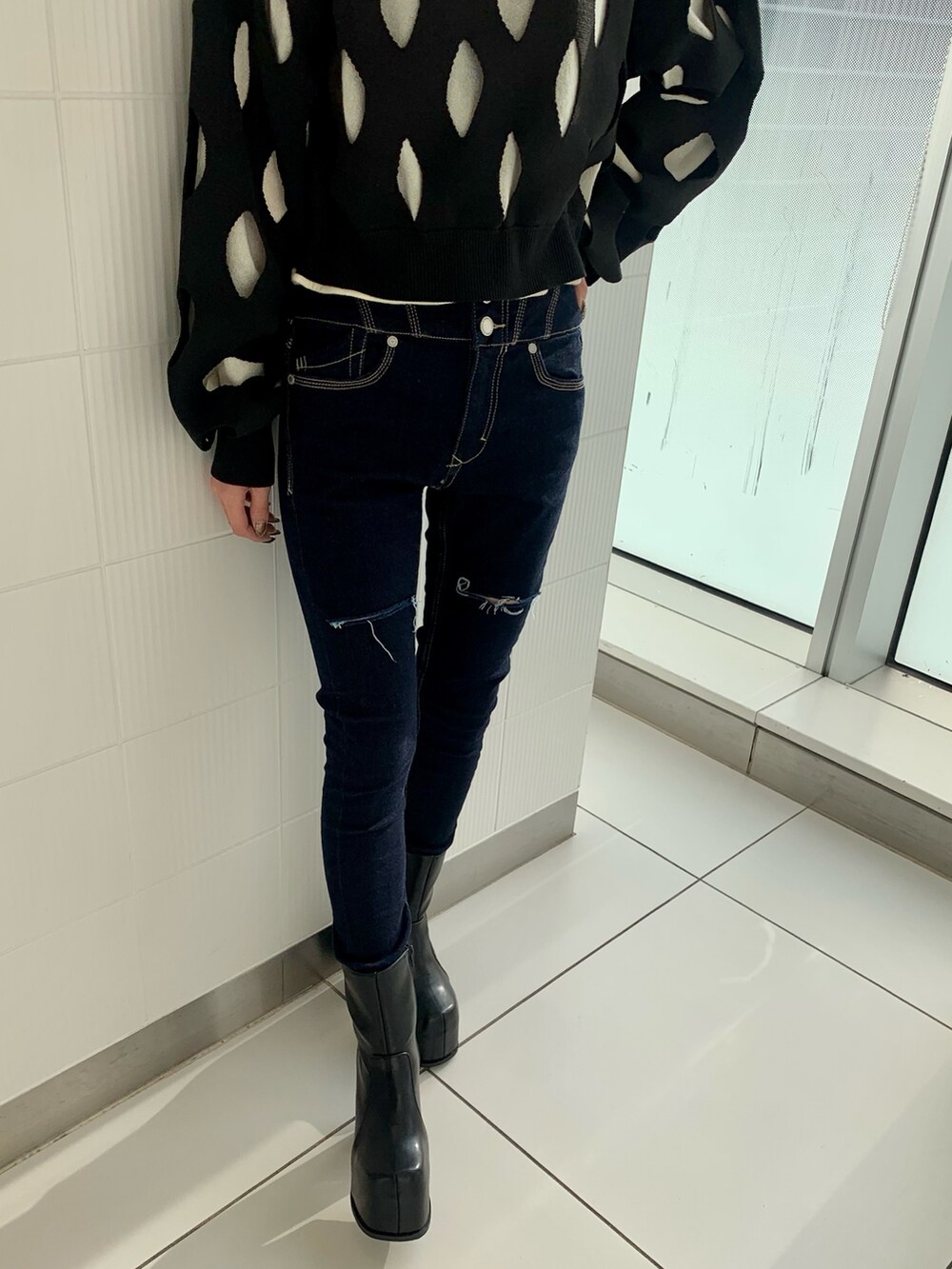 ブルー系のデニムパンツ、ブラック系のニット/セーター、ブラック系のブーツを着用したレディースの冬コーディネートの3枚目の写真