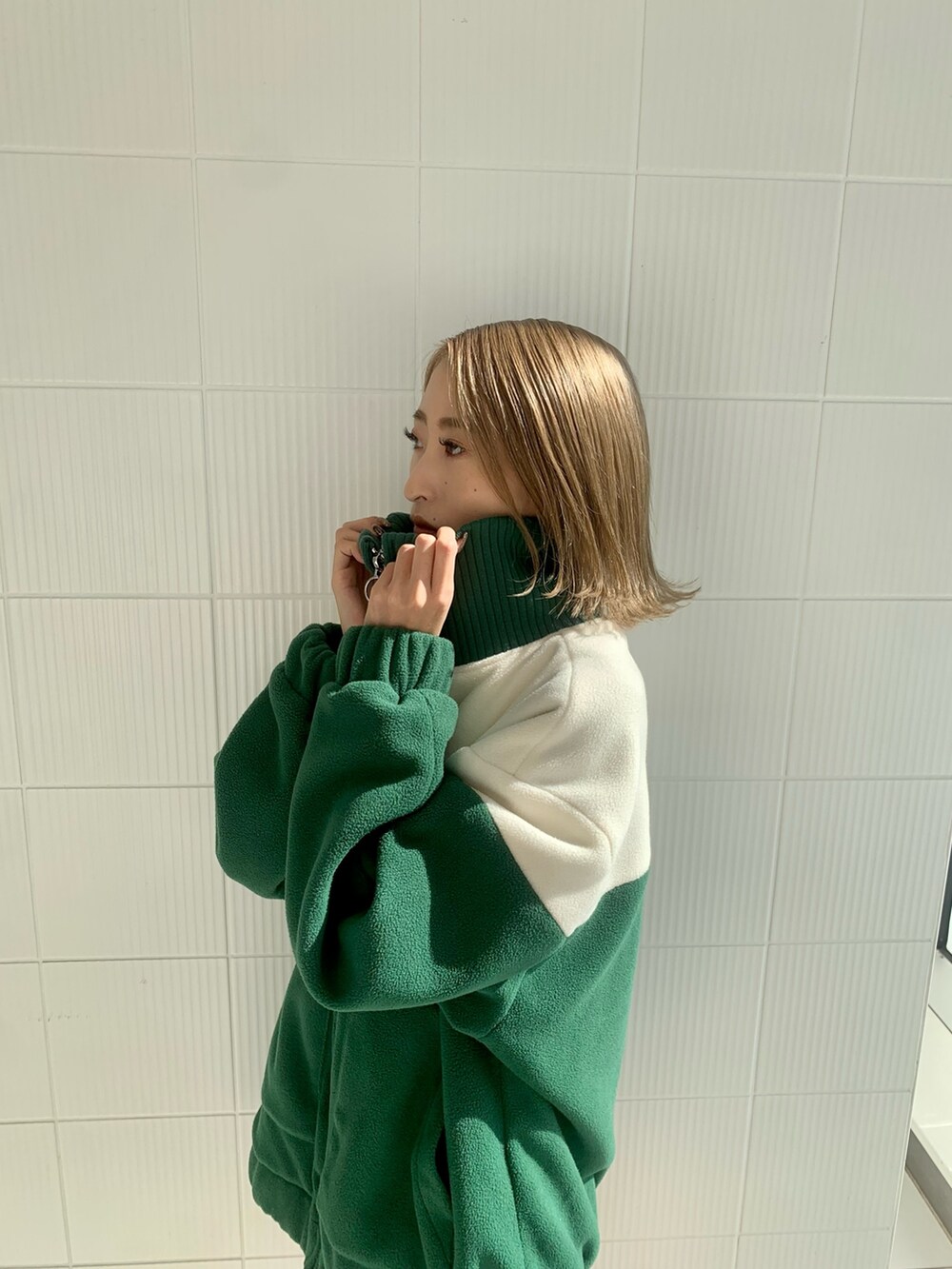 グリーン系のブルゾン、ブラック系のハンドバッグ、ブラック系のブーツを着用したレディースの秋コーディネートの2枚目の写真