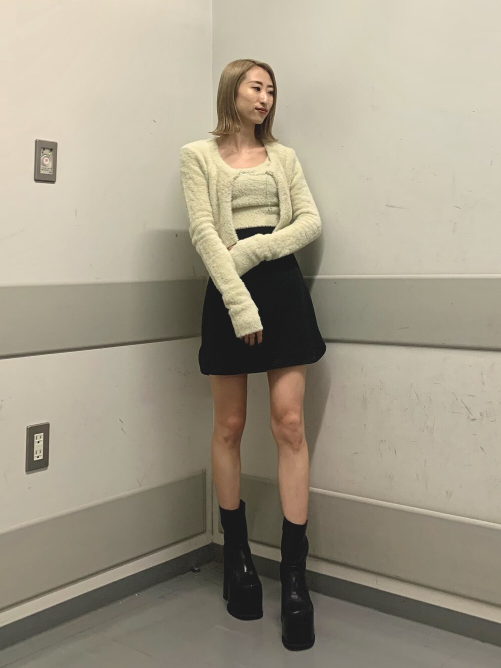 ブラック系のスカート、ホワイト系のニット/セーター、ブラック系のブーツを着用したレディースの冬コーディネートの4枚目の写真